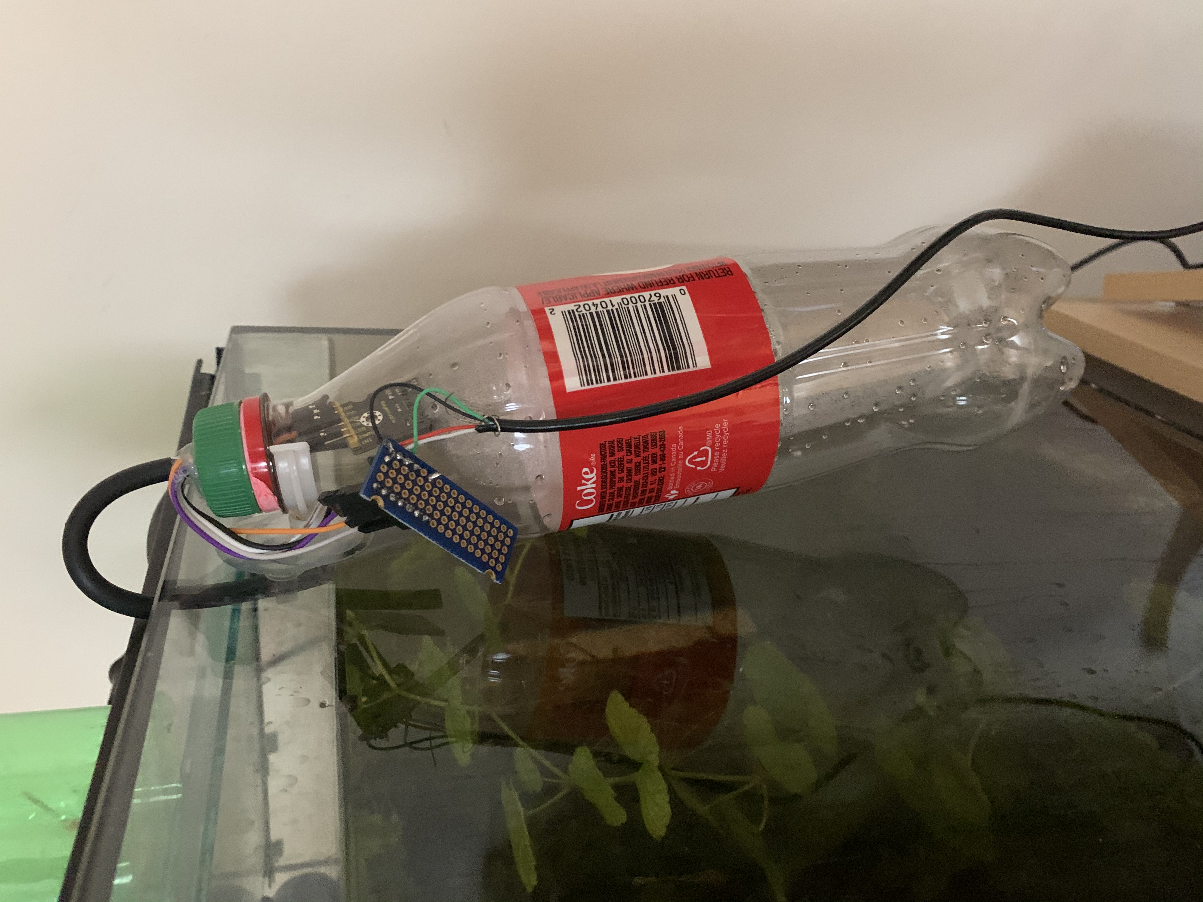 The bottle is in the outside of the tank, and the tubing leads from the coke bottle, to the tank.